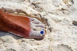 Woman feet with blue nail polish on the bach photo