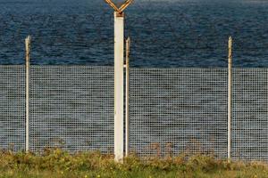 Detalle de cerca de alambre de púas cerca del mar foto