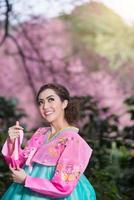 hanbok, el vestido tradicional coreano y hermosa chica asiática con sakura foto