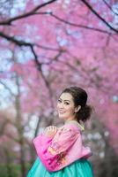 hanbok, el vestido tradicional coreano y hermosa chica asiática con sakura foto