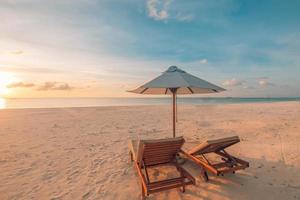 Relaxing sunset beach, summer vacation and holiday concept. Beach sunset view loungers and umbrella. Luxury travel landscape, exotic nature background. Paradise island view photo