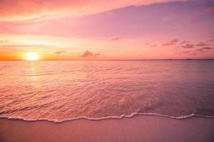 Dreamy beach scene with stunning waves. Colorful ocean beach sunrise or sunset, colorful bright sky and sun rays. Inspirational shoreline with soft tropical waves and relaxing mood. Peaceful, serene photo