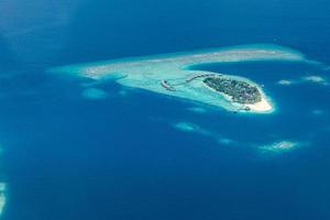 Aerial view of Maldives resort, luxury travel destination. Birds eye view of deep blue sea, coral reed, tropical island. Amazing nature view, drone aerial landscape photo