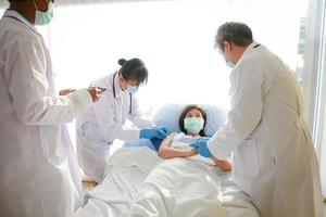 Doctors vaccinated against the coronavirus in an Asian woman wearing a mask lying on a hospital bed. The doctor shook hands to encourage the patient. The concept of medical service in a hospital photo