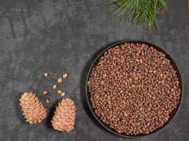 Pine cones and nuts in a frying pan on a dark background with space for copying photo