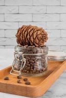 Pine nuts in a jar and a pine cone in the kitchen on a light background. photo