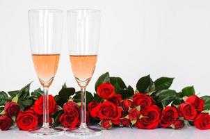 Two glasses of Rose wine on white background with red roses for Valentines dining concept. photo