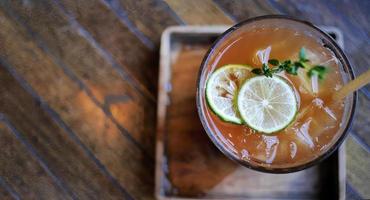 Directly above view, Selective focus a glass of refreshing cold soft drink lemon iced tea in ice cube with paper straw, decorated with sliced lime and thyme branches, summer drink photo