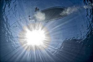 boat ship from underwater blue ocean with sun rays photo