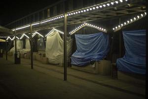 Closed market at night. Market in dark. Blue and white awnings. Lamps in building. photo