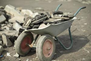 carro de jardín con asfalto. asfalto roto dentro del carro. limpieza de residuos de construcción. foto