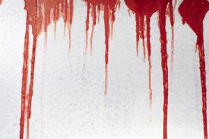 sangre roja en la pared. la pintura roja gotea por la pared gris. manchas de inscripción. foto