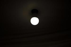 Lamp on ceiling. Light in dark room. Lamp is in interior. photo