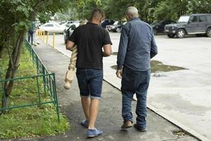 Men go on business in summer. People in yard of house. Young and old gathered case. photo