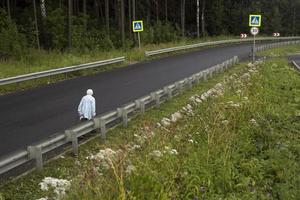 Old woman walks on empty highway. Woman on road. Pensioner walks. photo