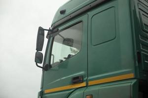 Truck cab on side. Green truck body. Transport details. Rear-view mirror of car. photo