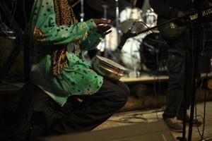 African plays drum. Reggae band performance. Playing there. Details of performance on stage. photo