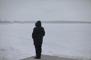 Man looks at snow lake. Woman in jacket. photo