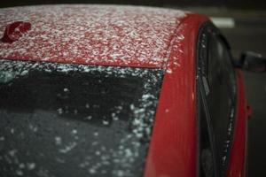 coche rojo en la nieve. partes de la carrocería del automóvil después de la precipitación. el coche está aparcado en invierno. foto