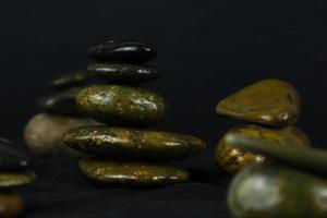 piedras oscuras en fondo negro usadas para conceptos relajantes como yoga, masajes y paz concepto de diseño de papel tapiz. foto