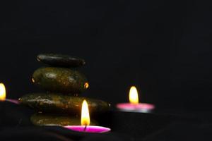 Layers of stones are on dark background, two rounded candles, use for massage and yoga obect concept photo