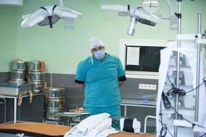 A doctor in a surgical suit stands in the operating room among the equipment.Portrait of surgeon in the operating room photo