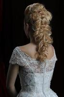 Blonde beauty hairstyle behind on a dark background beautiful.The long hair of the bride is neatly styled. photo