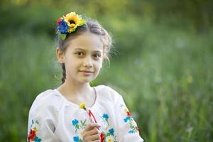 una niña ucraniana y bielorrusa con una camisa bordada en un fondo de verano. foto