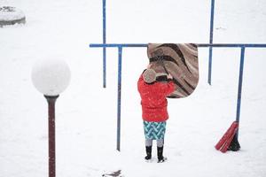 una mujer limpia la alfombra en invierno. foto