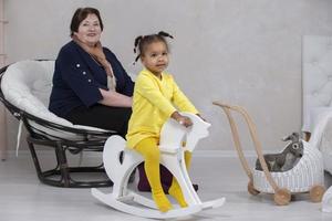 Grandmother and granddaughter from different races. The fair-skinned grandmother plays with the dark-skinned granddaughter. photo