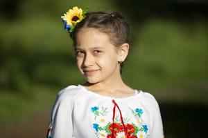 una niña ucraniana y bielorrusa con una camisa bordada en un fondo de verano. foto