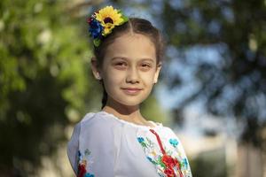 A little Ukrainian and Belarusian girl in an embroidered shirt on a summer background. photo