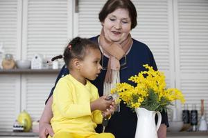 Grandmother and granddaughter from different races. The fair-skinned grandmother plays with the dark-skinned granddaughter. photo