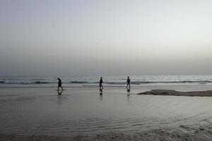 playa solitaria con gente paseando por la arena al borde de las olas del mar foto