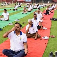 nueva delhi, india, 21 de junio de 2022 - sesión grupal de ejercicios de yoga para personas en el complejo deportivo yamuna en delhi el día internacional del yoga, gran grupo de adultos que asisten a clases de yoga en el estadio de cricket foto