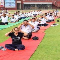 New Delhi, India, June 21 2022 - Group Yoga exercise session for people at Yamuna Sports Complex in Delhi on International Yoga Day, Big group of adults attending yoga class in cricket stadium photo