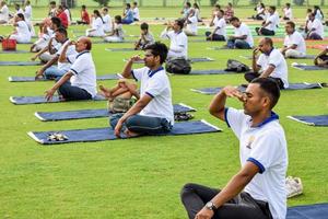 New Delhi, India, June 21 2022 - Group Yoga exercise session for people at Yamuna Sports Complex in Delhi on International Yoga Day, Big group of adults attending yoga class in cricket stadium photo