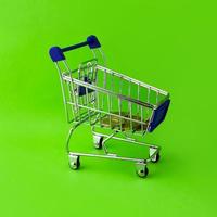 Shopping cart with euro coins on a green background. photo