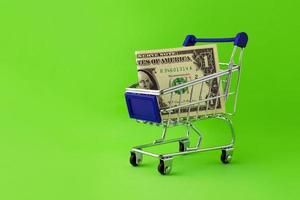 Shopping cart with a bill of 1 dollar on a green background.