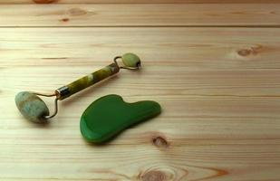 Jade roller and gouache scraper on a wooden table. photo