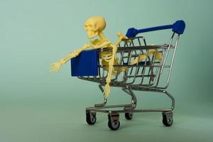 creative minimalist composition, a skeleton riding on a supermarket cart, turquoise background, a skull photo