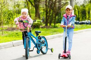 grupo interracial de niños con bicicleta y scooter sonriendo foto