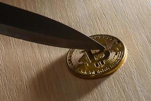 hoja de un cuchillo en una moneda de oro bitcoin foto