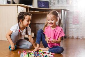 Two little children are playing with blocks happy girls at home funny lovely sisters photo