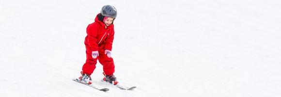 Little girl in red learning to ski photo