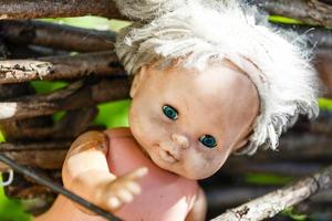 Abandoned old broken baby doll rots in scary forest photo