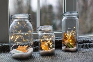 Beautiful lights, garland in a jar with textile red plush hearts and rose petals on a wooden background. Love or valentine's day concept photo