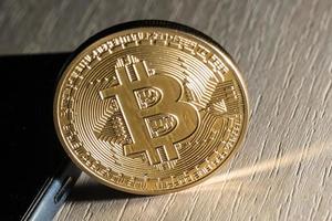 Close up of a golden bitcoin currency and a smart phone photo