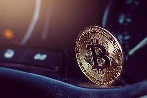 gold bitcoin on the dashboard of the car next to the fuel consumption