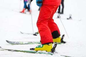 Skier in red ski suit and yellow ski shoes, close up photo